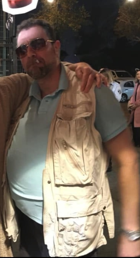 Naf at night in amber tinted glasses and a khaki fishing vest, fully in character as Walter